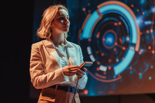 On-Stage Successful Female Speaker Presents Technological Product, Uses Remote Control for Presentation