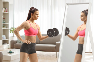 Female exercising with a dumbbell in front of a mirror