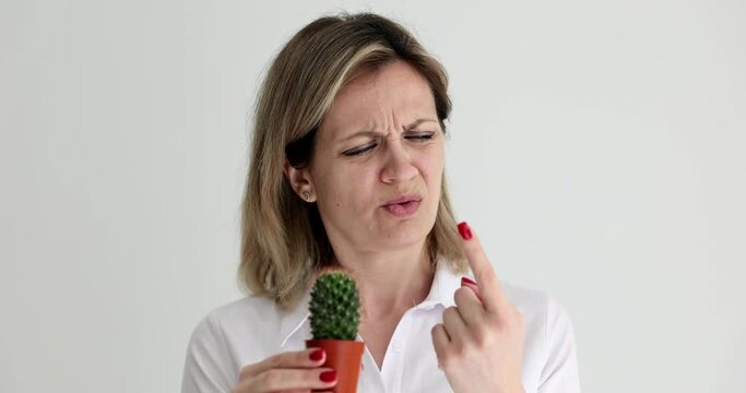 Woman pricking her finger on cactus in pot 4k movie slow motion. Hand eczema symptoms concept