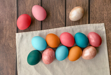 A variety of colorful Easter eggs rest on a white cloth atop a wooden table, creating a sweet and festive confectionery display of food ingredients
