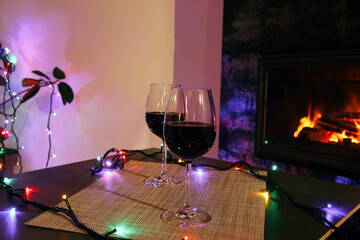 Two glasses of wine near the fireplace in the evening. Cozy evening by the fire