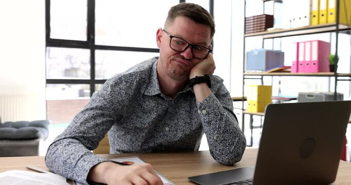Businessman with glasses bored and tapping fingers on table in front of laptop in office 4k movie. Time management concept
