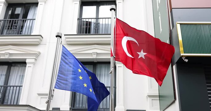 Turkish and European Union flags fluttering in wind near embassy 4k movie slow motion. International interactions of countries and beneficial cooperation concept