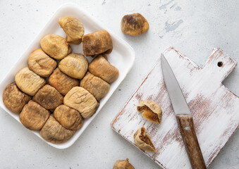 Organic dried sweet figs with chopping board and knife on white kitchen background.Top view.