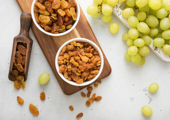 Sweet green raisins in bowl and scoop with grapes in wooden box on light kitchen background.Top view.