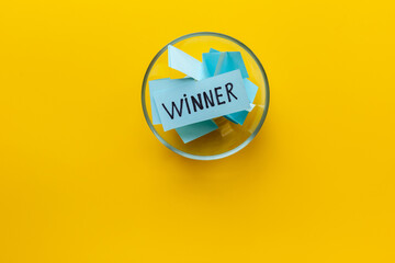 Winner concept. Lottery winner ticket in glass bowl full of paper sheets - 777110360