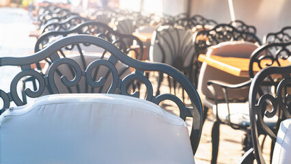 Sunny street cafe ambiance with elegant metal chairs and wooden tables, ideal for relaxed urban...