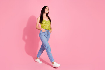 Photo of pretty nice positive girl wear stylish clothes walk look empty space isolated on pink color background