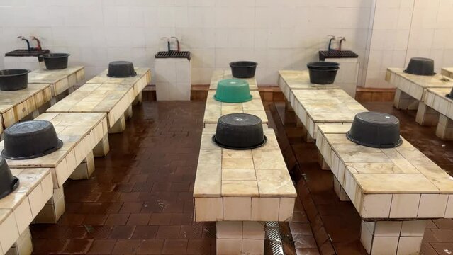 A public place for washing the body in economy class in a public bath for people. Plastic bowls for collecting water are on granite tables