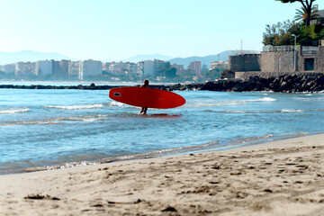 Man kayaker carries a surfboard, a kayak on a coaster against the backdrop of the city and a...