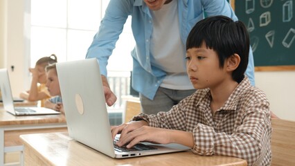 Caucasian teacher helping asian student coding engineering prompt while diverse student using...