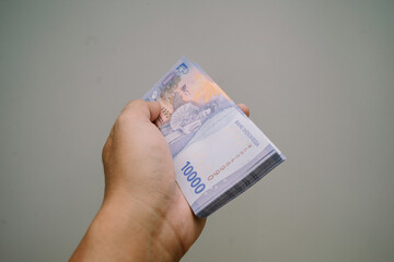 A wad of 10,000 rupiah bills, still sealed with the bank logo, was placed on a white mat. This money is to be distributed to children on Eid