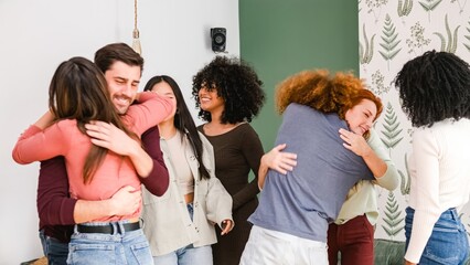 Multiethnic excited friends embracing each other during weekend party at home