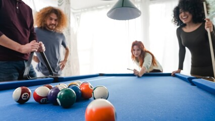 Woman playing pool with diverse friends at home on weekend