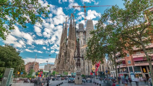 Sagrada Familia Splendor: Timelapse Hyperlapse of the Iconic Catholic Church in Barcelona, Spain. Autumnal Tranquility with Green Trees and a Pensive Blue Cloudy Sky