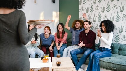 Diverse friends cheering up for anonymous woman bringing pizzas during party at home