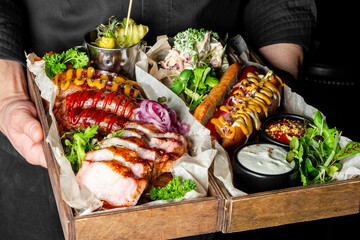 A wooden tray brims with an enticing array of grilled meats, sausages, and fresh vegetables,...