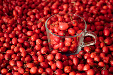 Rose hip or rosehip inside of the glass and over the table. Empty space for copy paste. Backgrounds and textures. Red vibrant colors. Cinematic. Wild fruits and healthy food.