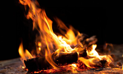 Cozy orange flames lick the firewood in a burning fireplace at night