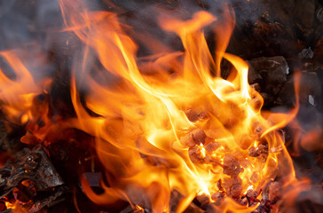 Cozy orange flames lick the firewood in a burning fireplace at night - obrazy, fototapety, plakaty