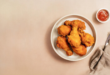 A plate of crispy fried chicken snacks, including nuggets and wings, some dipped in a delicious sauce, on a  background
