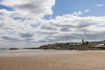 The serene beach of St Andrews, Scotland, sets the stage for a stunning view of the town historic skyline, marked by traditional buildings and a prominent church spire