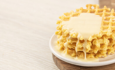 waffles and condensed milk on a light background, top view. copy space