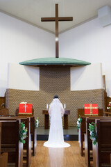 Bride appearance from behind wearing a beautiful white dress in Catholic Church. It is a happy...