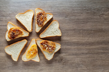 Slices of bread with apricot jam on wooden background
