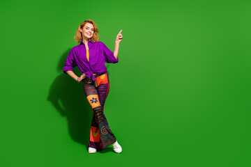 Photo portrait of lovely young lady point empty space poster dressed stylish violet clothes isolated on green color background