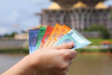 Hand with Malaysian ringgit paper money - 777157717