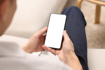 Man using smartphone with blank screen indoors, closeup. Mockup for design