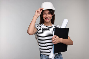 Architect in hard hat with draft and folder on light grey background