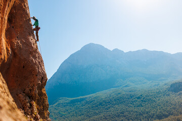 A girl climbs rocks, a rock climber against the backdrop of a mountain, a sporty girl is engaged in...