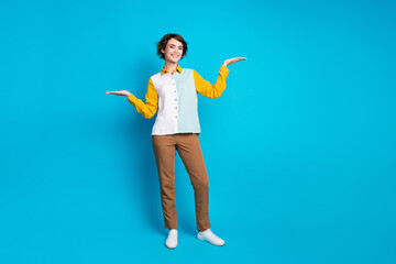 Full length photo of good mood cute lady dressed shirt compering two arms empty space isolated blue color background