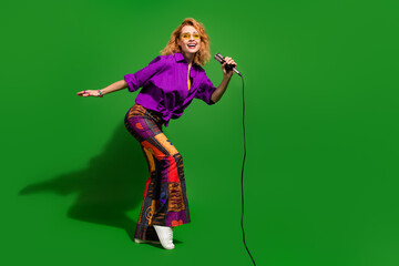 Photo portrait of lovely young lady singing enjoy karaoke dressed stylish violet clothes isolated on green color background