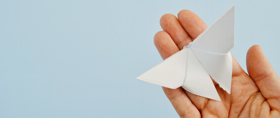 White paper origami butterfly on blue background. World Day of Peace. Day Against Humiliation....