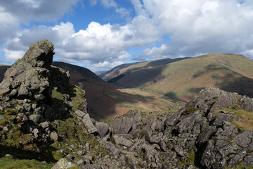 Rocky outcrop of the Lion and Lamb at the top of Helm Crag in the Lake District National Park. Cumbrian fells can be seen in the backdrop.