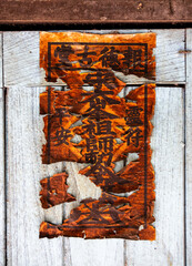 Incomplete.  Burnt paper with Chinese symbols stuck to a wooden door.