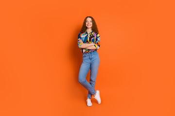 Fototapeta na wymiar Photo of lovely pretty nice cheerful girl wear trendy clothes crossed arms empty space isolated on vivid orange color background