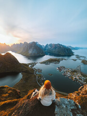 Woman traveling in Lofoten islands hiking Reinebringen mountain, girl enjoying sunset aerial view in Norway summer active vacations solo traveler outdoor healthy lifestyle adventure trip - obrazy, fototapety, plakaty