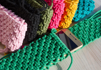 Small handbag for a mobile phone. Knitting macrame, pattern of multi-colored cotton cords. Handmade concept, hobby.