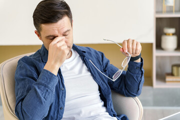 A man experiences a moment of fatigue or eye strain, taking a break by removing his glasses in a...