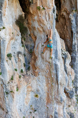 A young and strong woman is rock climbing on a rock.