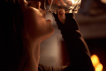 Beautiful sexy brunette pours a glass of drink over herself - obrazy, fototapety, plakaty
