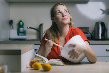 Young mature woman is making a dinner. Woman stirring food in a bowl. Red shirt on a woman,...