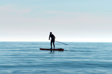 Silhouette of a kayaker on a personal rowing kayak, rowing a kayak with an oar in the calm waters...
