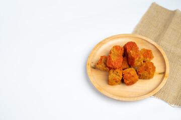 Crispy tofu in a wooden plate with a sprinkling of balado powder