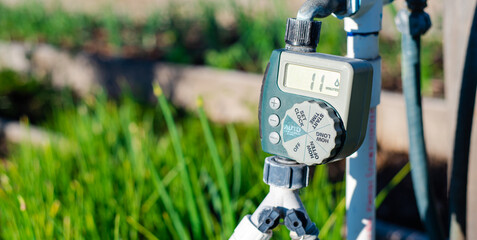 Panorama large display of water timer at community garden in Dallas, Texas, outlet hose faucet digital timer with Y splitter connector automate drip irrigation system, water energy conservation - obrazy, fototapety, plakaty