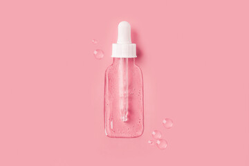 Cosmetic jar with a dropper in the form of a transparent gel spilled  on a pink background.